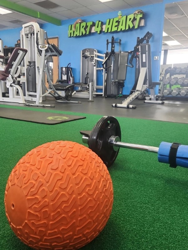 Orange textured medicine ball and barbell set up on green artificial turf in Cook County.