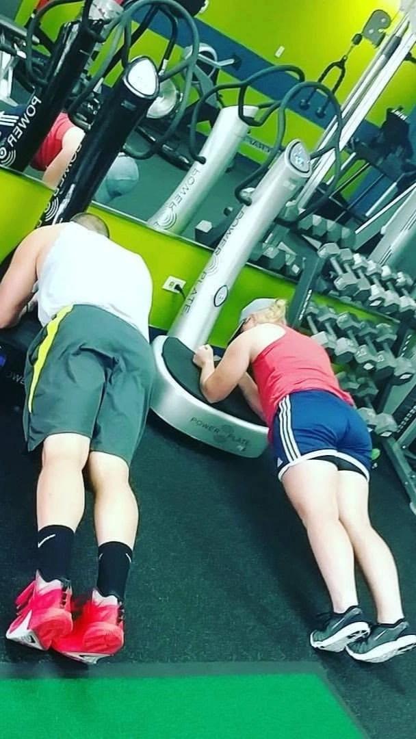 Two people holding plank positions on vibration Power Plate machines inside a Palatine studio.