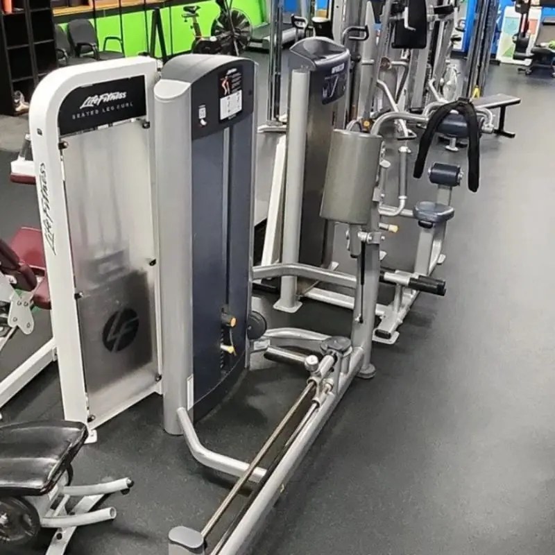 Pin selected weight machines including a leg curl aligned inside a clean custom workout facility in Arlington Heights, IL.