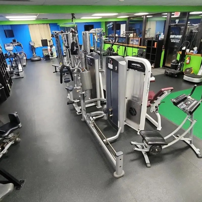 Modern resistance training machines arranged neatly on a dark floor inside a personal fitness studio in Palatine, IL.